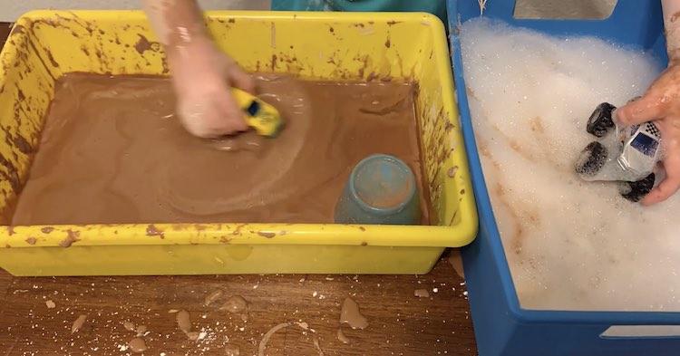 One bin of soapy water alongside a bin of muddy oobleck. One monster truck in each bin.