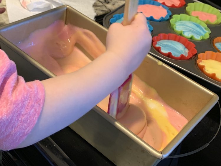 Zoey mixing the loaf pan up while the poured cupcakes sit in the background.