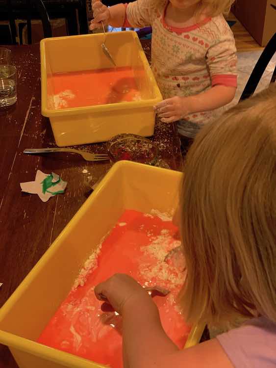 Ada and Zoey playing with red and orange oobleck.
