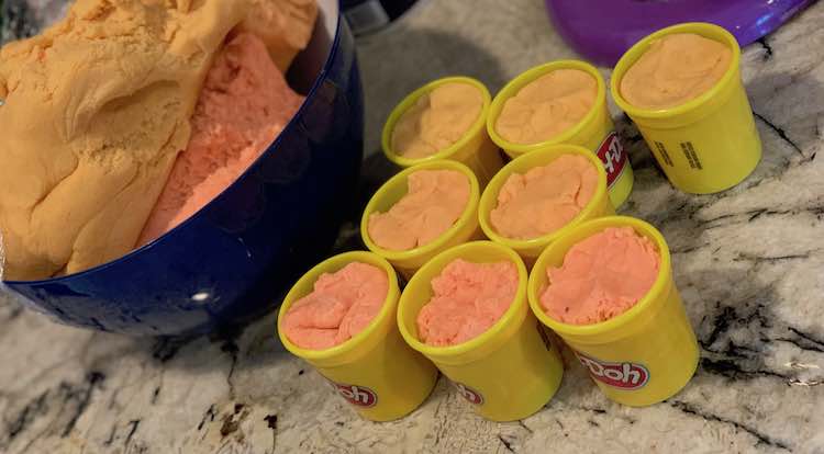 Play-Doh containers filled with homemade orange playdough.
