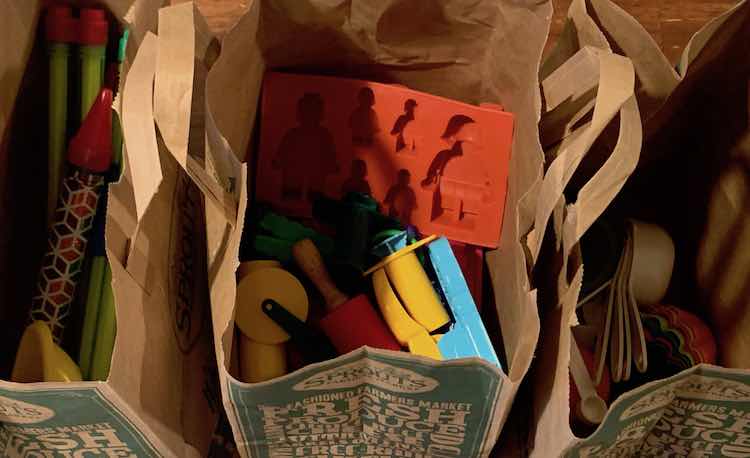 Three paper bags side by side with sensory tools in them.