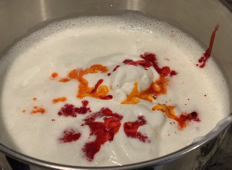 Bowl with foamy white and dribbles of red or orange.