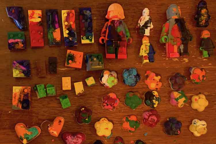 All the multicolored crayons laid out on the top of the kitchen table. There's LEGO bricks, LEGO people, flowers, and hearts.