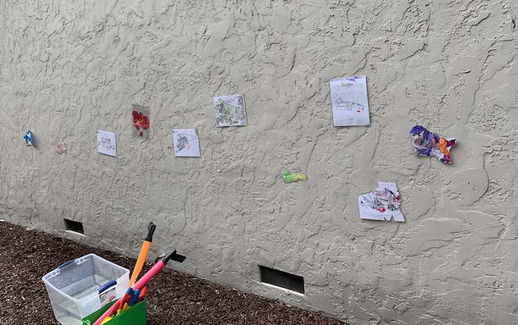 All the targets attached to the wall with the water guns contained in an old DUPLO® box and a bin of water beside it.