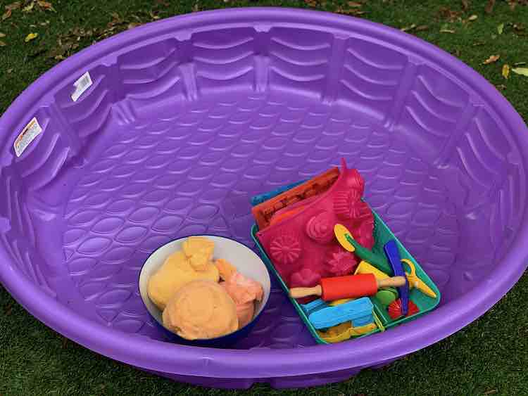 Empty purple plastic pool with the playdough stuff inside.