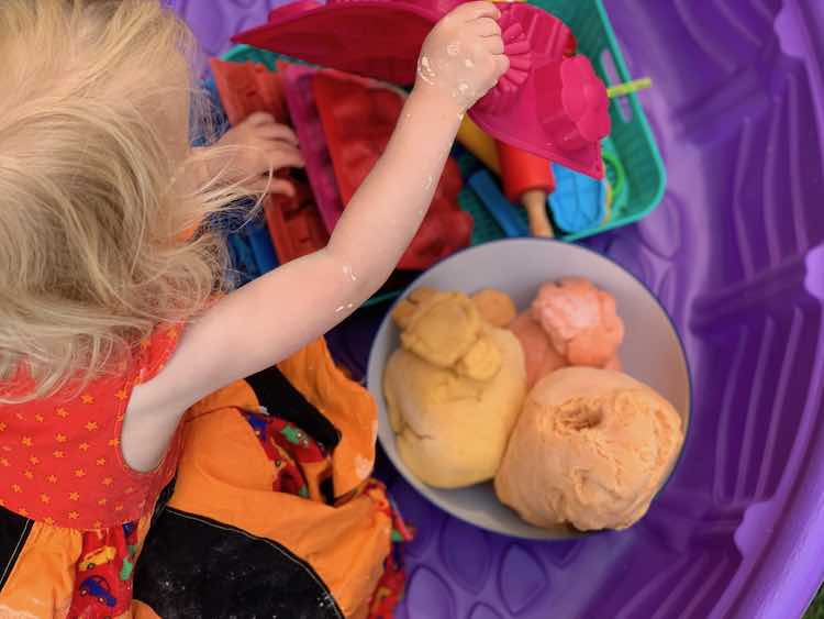 Zoey crouched over the playdough pulling out the flower mould.