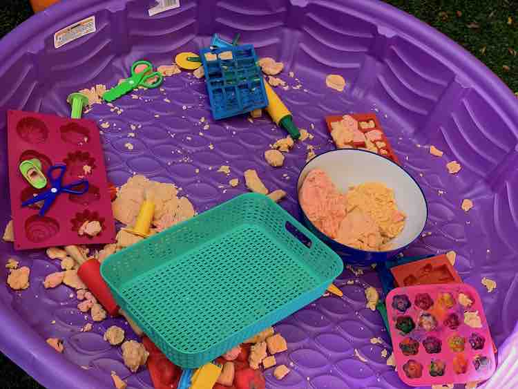 Dry pool filled with playdough bits and playdough tools.