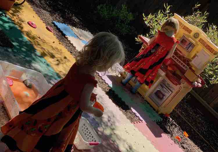 Zoey in the foreground holding a cupcake liner of oobleck and Ada in the background at the kitchen set.