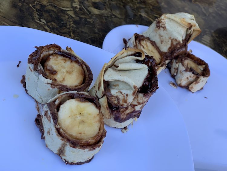 Image shows sliced tortilla wrapped banana with Nutella.