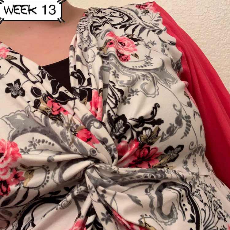 Closeup of another Mariella top. This one has white fabric with pink flowers and vines in black and grey over it. The arm showing in the back of the image is made of pink fabric. 