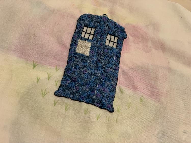 TARDIS with a mostly flatly colored background and some grass lines in the ground.