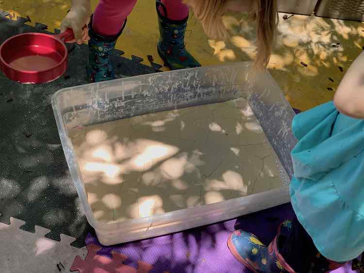 Kids posed to break apart the bin of desiccated oobleck.