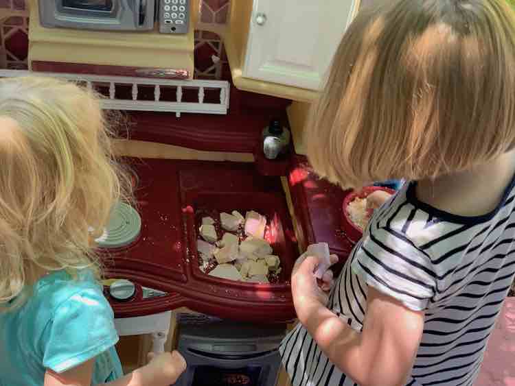 Kids in front of a kitchen set. Sink has flat chunks of dried up oobleck while Ada stands in front of a frying pan of 'sand' holding an unbroken piece in her left hand.