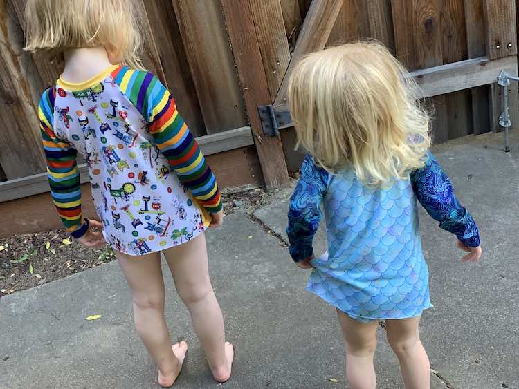 Kids showing off the back of their swimming suits.