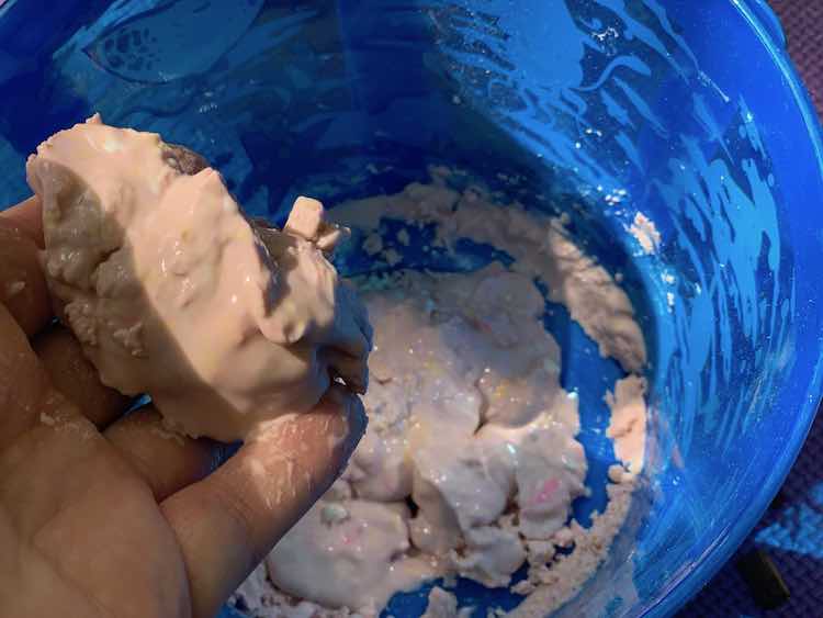 Re-hydrated oobleck glistening and slowly dripping out of my hands back into the pail. Out of shot Zoey about to sprinkle more dried oobleck into the pail as I take photos. 