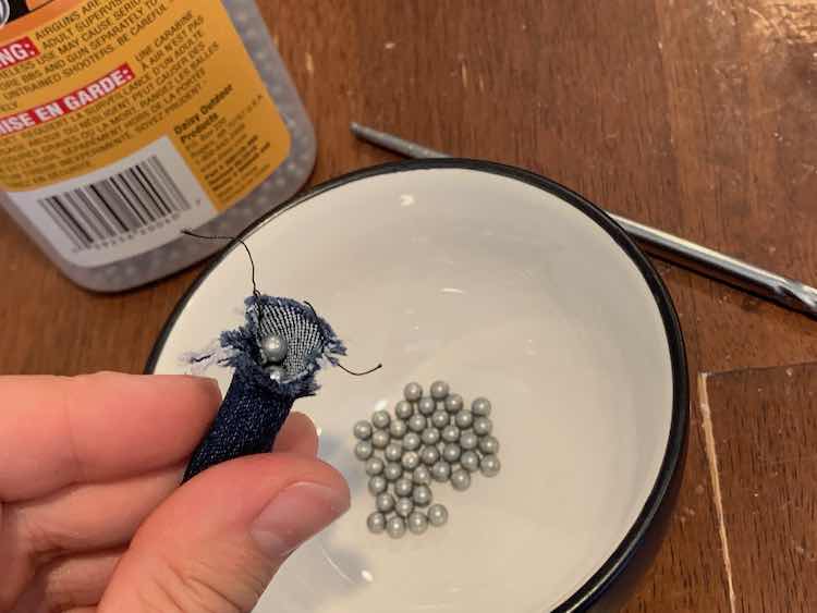 Stuffing pellets into the end of the pattern weight. The background shows the extra pellets in a bowl, the container of pellets, and a chopstick.