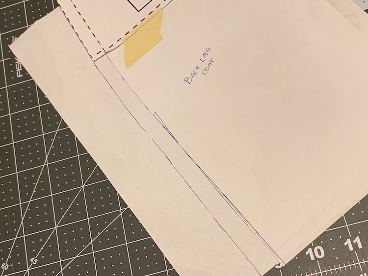 The bottom left corner of the pattern piece is showing. It's taped to a large piece of paper. The bottom is flat and the left side has the new pattern piece edge drawn in.