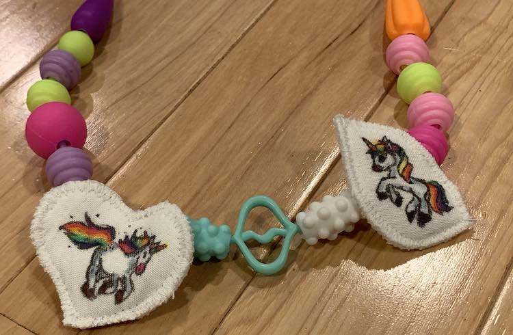 Both pendants attached to snap beads to make a necklace. The pendants are separated by three beads with beads trailing from the pendants into the background edge.