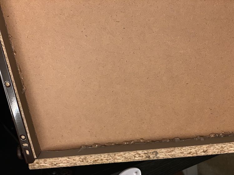 Overhead view of part of the bottom of the dresser drawer showing the glue holding it together.