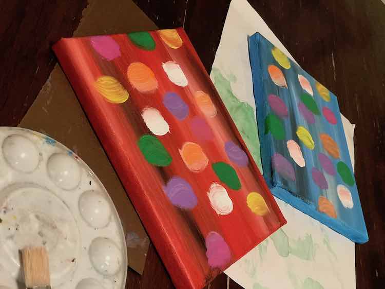Both canvases with the background and balloons painted on. The cleaned off paint palette and paintbrush are off to the left.