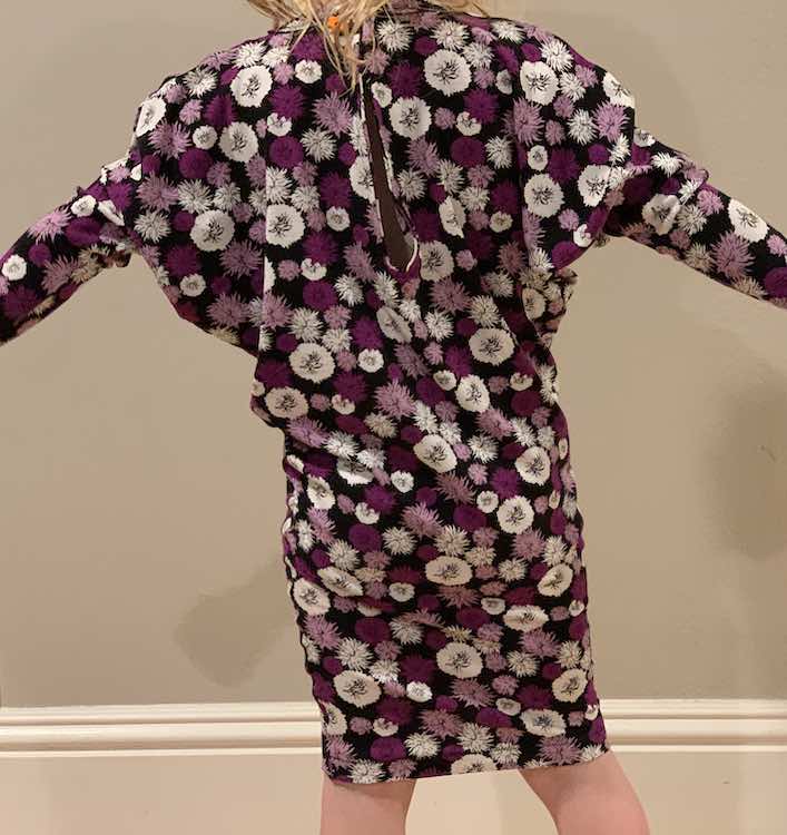 View of the back of Zoey’s with her arms raised to the sides. The entire height of the dress is shown but the end of the arms are outside of the photo. 
