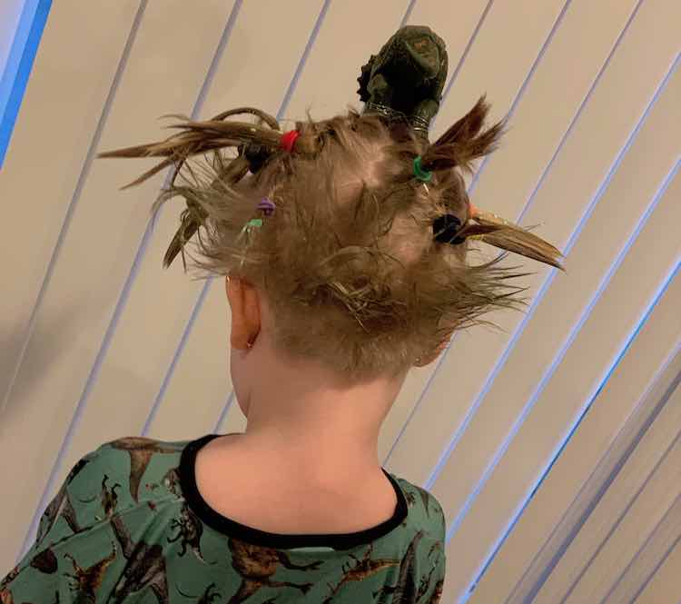 Full lower back view of Ada's dinosaur hair do with her dinosaur dress on.
