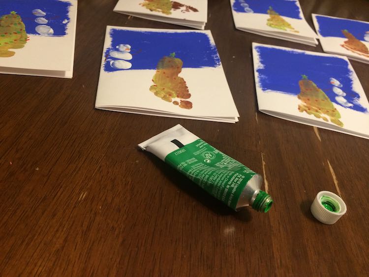 Several cards are in the background of the image showing red lights, yellow stars, and orange carrots. In the foreground you see an opened tube of green acrylic paint.