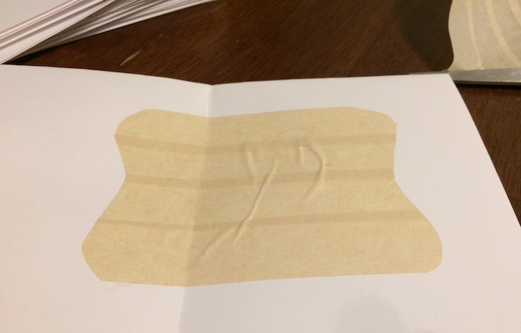 Opened card with a curved square shape of masking tape stuck to the inside. 