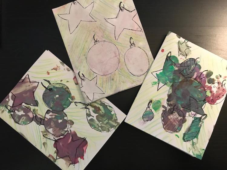 Three cards are in the image. The middle one has very faint, almost white, ornaments while the other two are more bold in green and burgundy. 