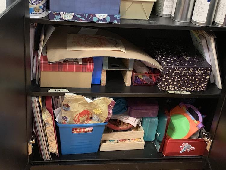 Open cupboard showing the shelves of an Ikea bookshelf with the kids art stuff separated and organized. 