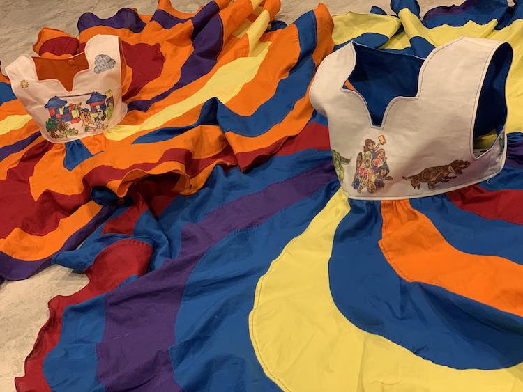 Image shows two dresses laid out on the kitchen floor. The skirts are flat so you can see the swirls while the bodices are held up as if they were being worn. 