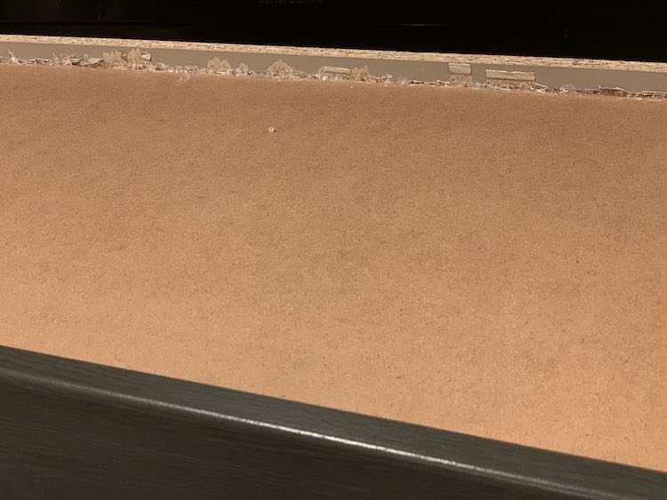 Underside of the drawer. The edge shows the new and old glue along with where you can see the paper peeled away from the wood from, probably, when the old glue released it's hold.