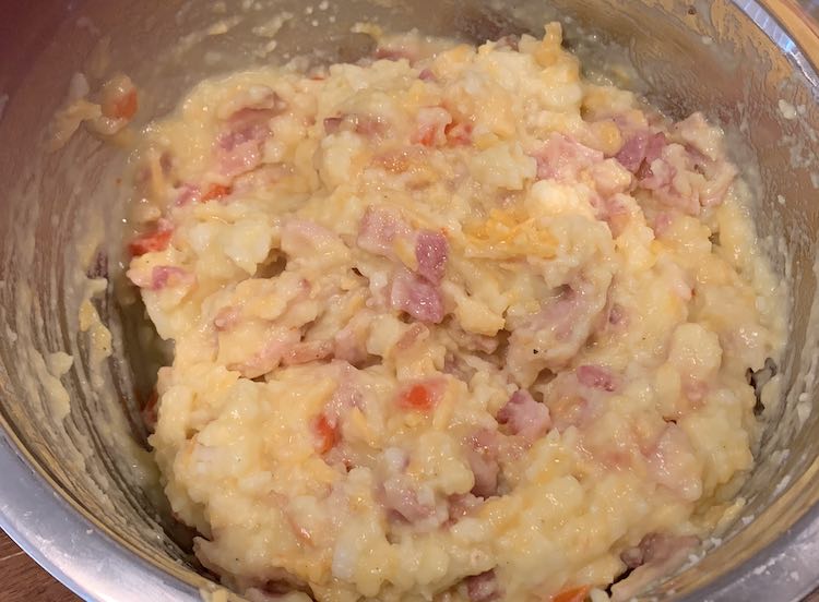 Metal bowl with all the various ingredients mixed up inside. You can more easily see the eggs now based on the yellower parts in the potatoes. 