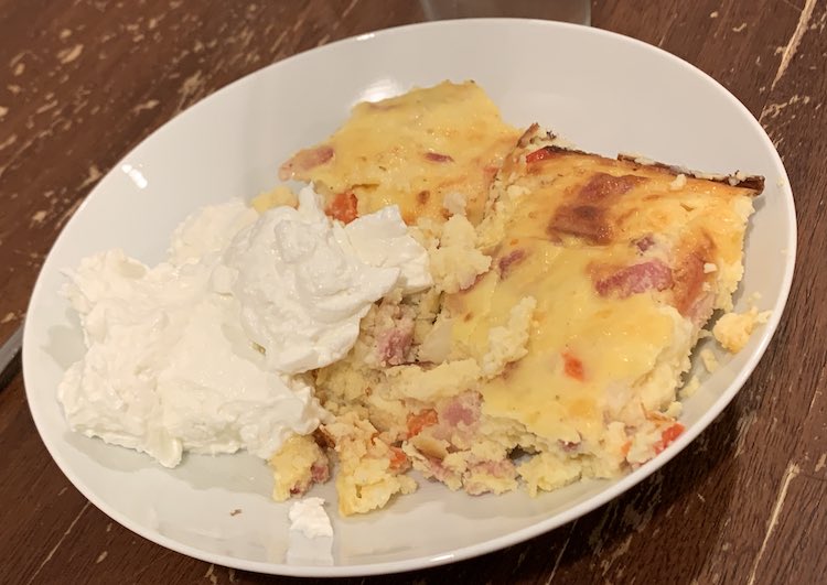 White plate with the yellow casserole on the right hand side and white pile of Greek yogurt on the left. 