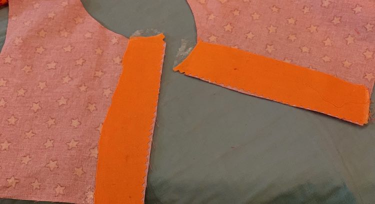Showing the wrong side of the outer layer of the bodice. The two cut edges, making up the back, are interfaced with the solid orange fabric. 