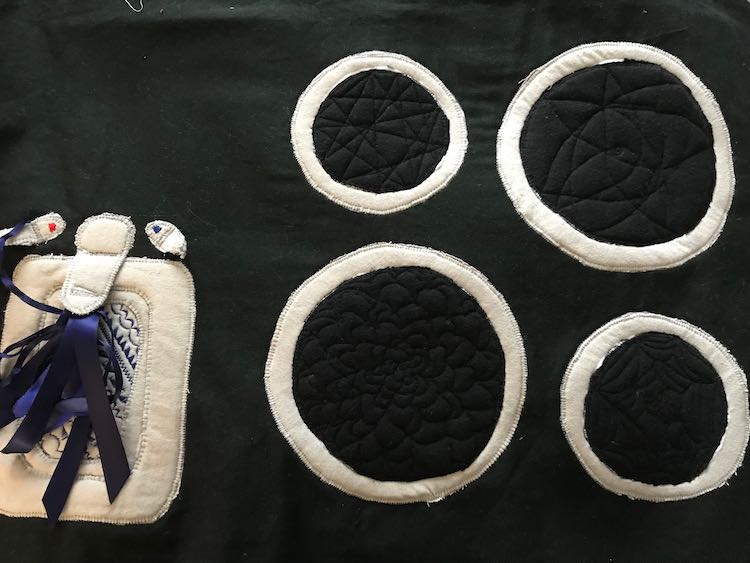 Right side of the image, again, shows the four burners. This time they are a range of valleys (where they were sewn) and hills (puffs from the interfacing in the space between). The top burners are easier to see in the light with the small left one being filled with lines and the right large one almost looks like a star or pointed petal flower.  The black thread blends in with the black flannel used for the burner so you can only tell where it was sewn based on the the hills and valleys. 