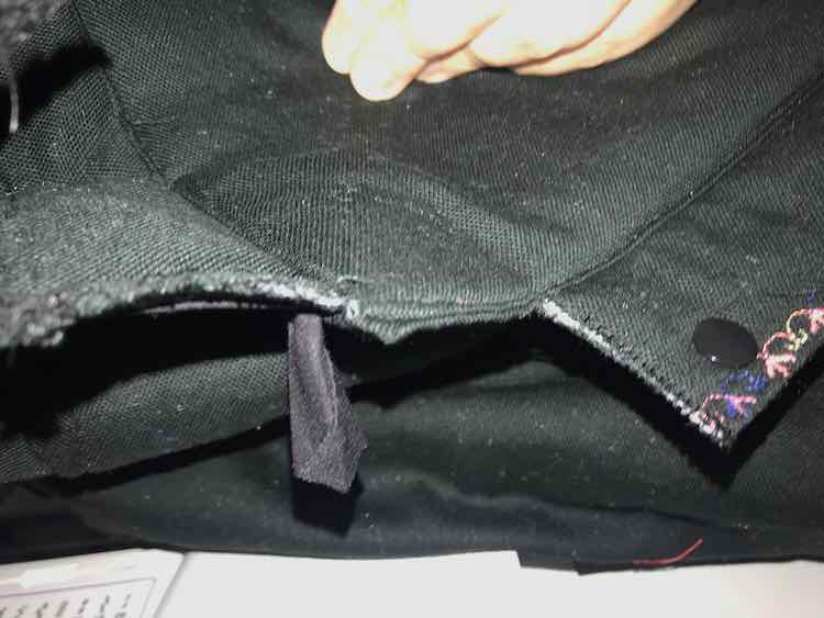 Closeup of the corner again. The left side of the image shows the front flap with the bias tape. The right side shows the side flap with a KAMsnap on it.
