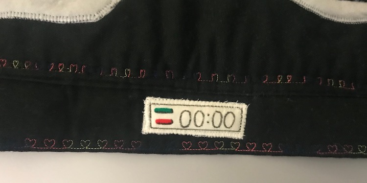 Timer sewn onto the black flap. If you look closely you can see the white stitches going around the outside of the timer keeping it in place. 