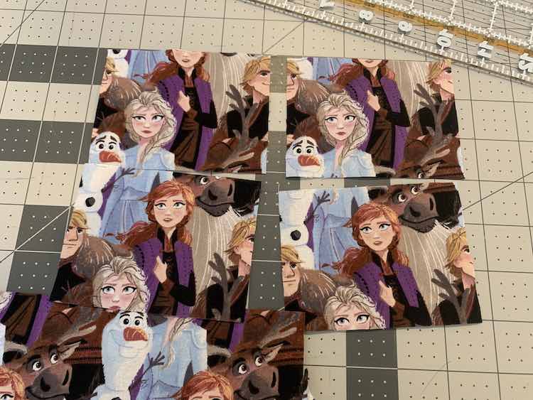 View of the four squares I cut out from the Frozen fabric I got from Walmart. The top two show Elsa's head with the surrounding characters cut off while the bottom two show, mainly, Anna. 