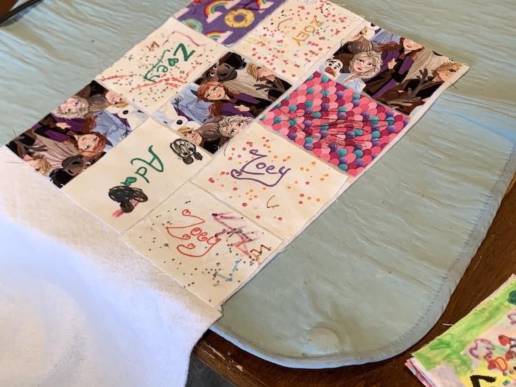 Showing ten of the sixteen rectangles laid out on the fusible fleece leaving a small border around each one. The bottom right side of the photo shows the remaining pile of rectangles that still needed to be laid out.