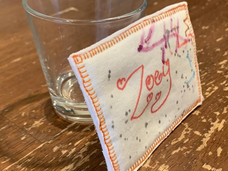 Closeup of Zoey's name tag leaned against a transparent empty glass.