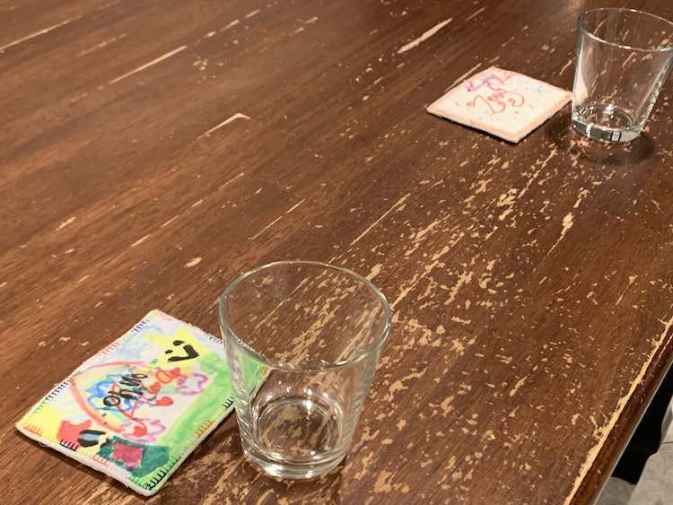 View of the washed off table with two transparent water glasses spaced a seat apart with the name tag laid out by each one. 