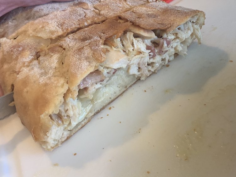 Closeup of the cut open sandwich bread filled with leftover chicken and bacon combined with diced brie.