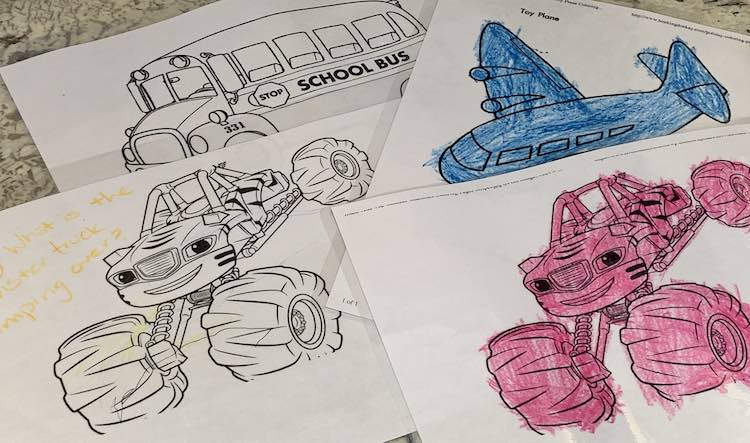 Four laminated images are spread out on the counter. Two shows a monster truck, one a blue airplane, and the last a school bus.