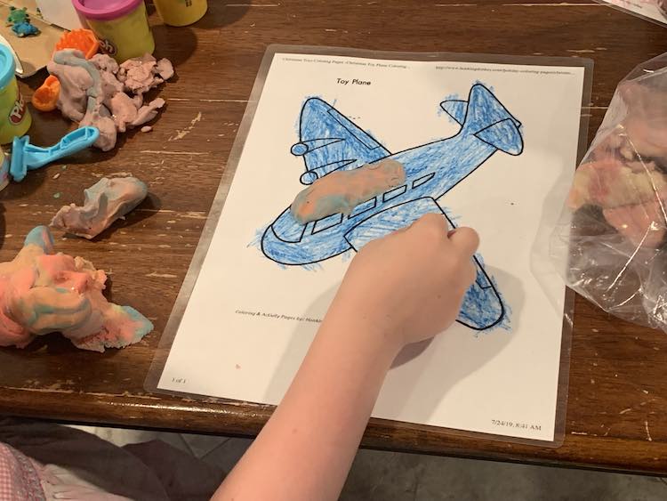 Image shows a blue colored airplane with some pink mottled playdough forming part of it's roof. 