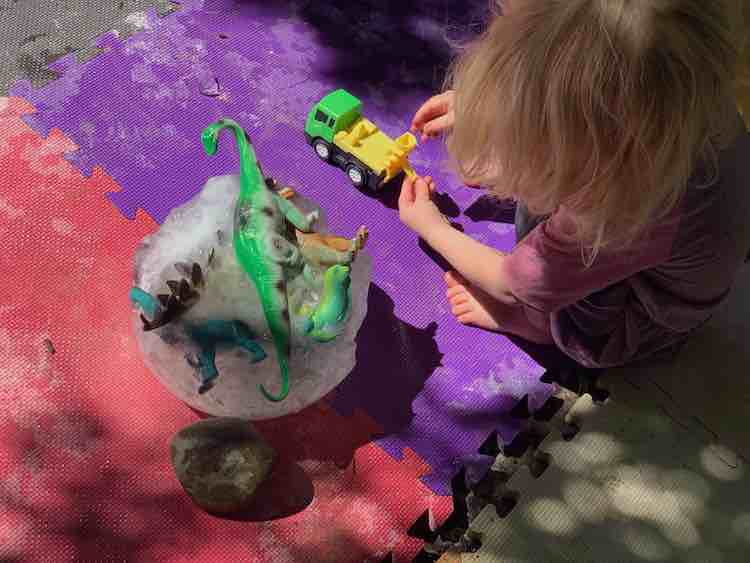 Closeup of the eroded ice ball with Zoey crouched beside it playing with her cement mixer. 