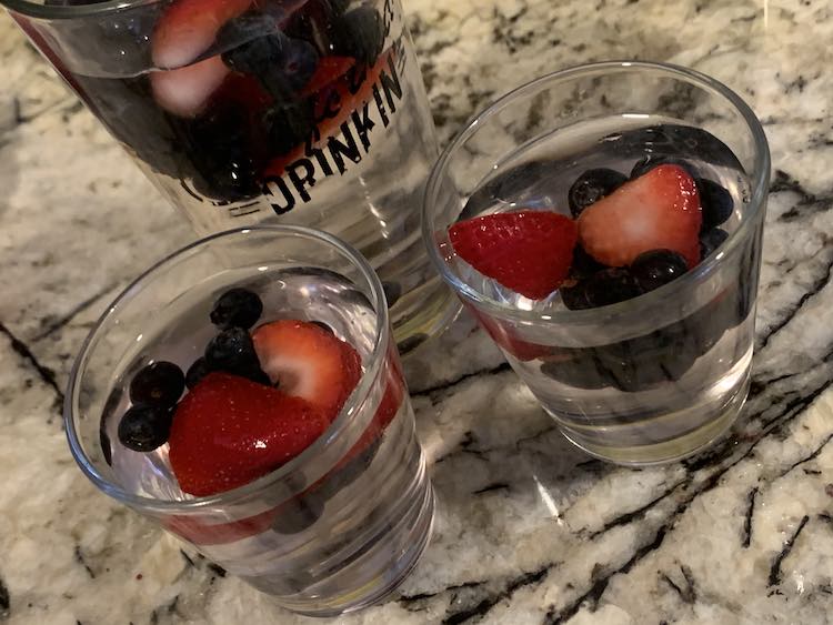 Showing my tall cup, cut off, and two small glass cups all with transparent water and floating frozen fruit.