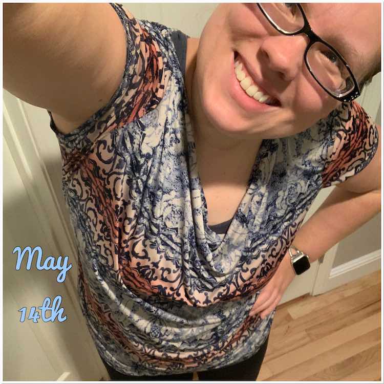 Selfie view with my head tilted and my other hand on my waist. Shirt drapes down in the neckline showing my matching blue brazi underneath. The fabric is a slinky ITY with horizontal blue, white, and pink patterns going across which showcases the draping.