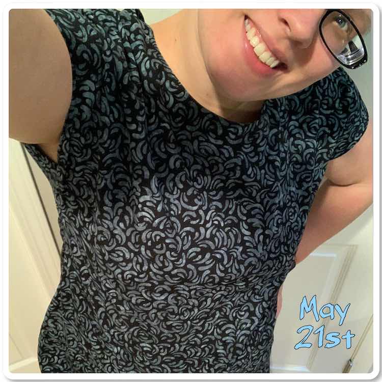 Tilted head selfie photo showing a woven shift shirt. The fabric is black with grey-ish blue curved patterns on it. The bottom of the photo cuts of the shirt. Beside the shirt it reads, in light blue with a black outline, 'May 21st'.