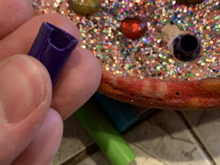 Closeup of the broken lid, in my hand, while, in the background, you can see the little bit of the lid left in the plaster. 